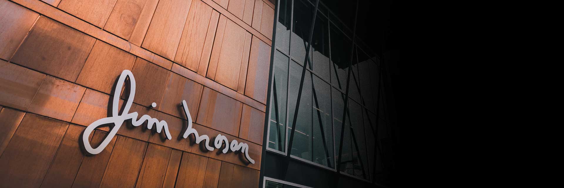 Exterior of the Jim Moran building featuring the cursive Jim Moran signature mounted on a warm wood-paneled facade